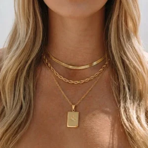 three-chain 18K gold layered necklace with geometric starburst pendant worn on model close-up