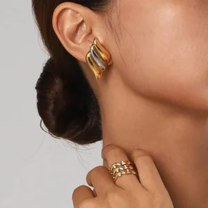 two-tone wing stud earrings worn on ear close-up side view model