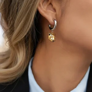 Two-tone 18K gold leopard hoop earrings worn on female ear close-up side view on blonde model in business casual professional outfit