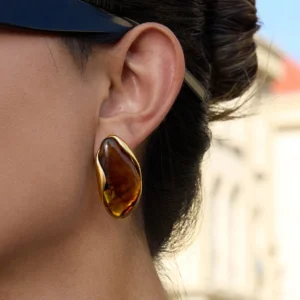 Single 18K gold amber marbled gemstone stud earring worn on ear outdoor lifestyle