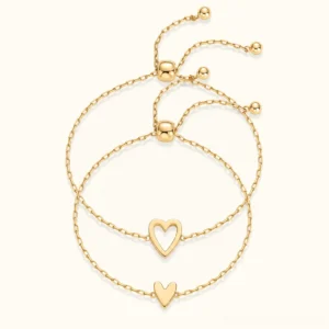 18K gold matching hearts bracelet set - two nesting heart charms on delicate cable chains with adjustable pull sliders, flat lay view