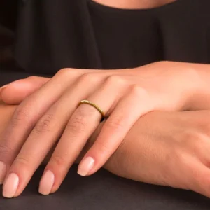 Slim 18K gold ring worn on hand with nude manicure, elegant minimalist jewelry styling on dark desktop