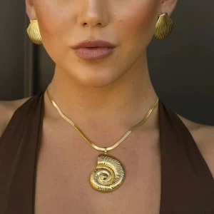 Model wearing 18K gold nautilus necklace and matching shell stud earrings set - close-up portrait shot with dark studio background