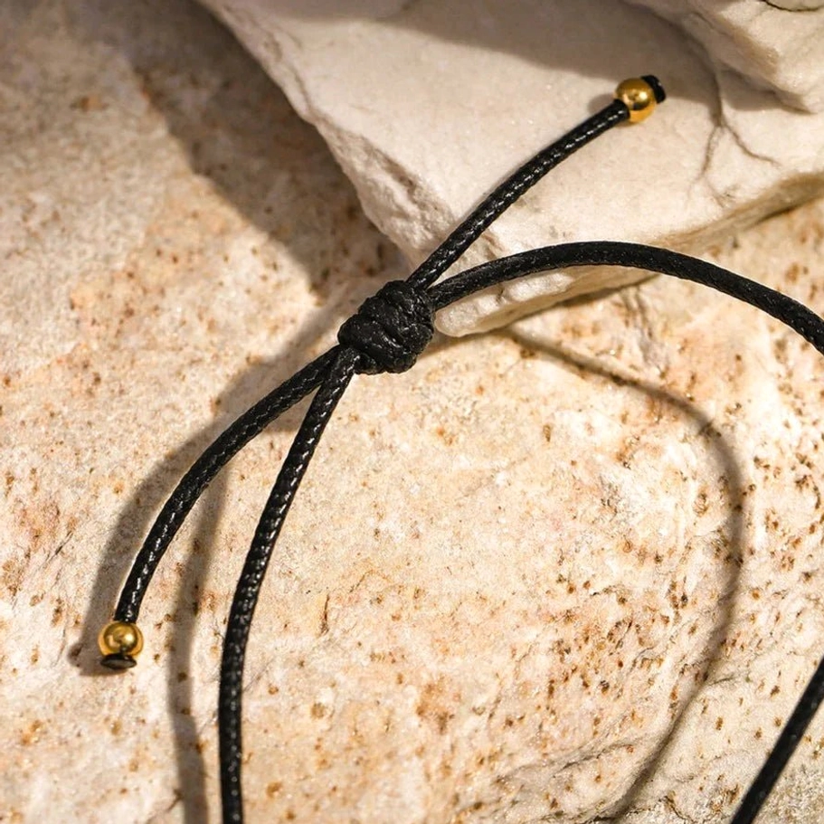 18K gold necklace black waxed rope cord adjustment mechanism showing metal toggle ends and knotted fastener clasp detail