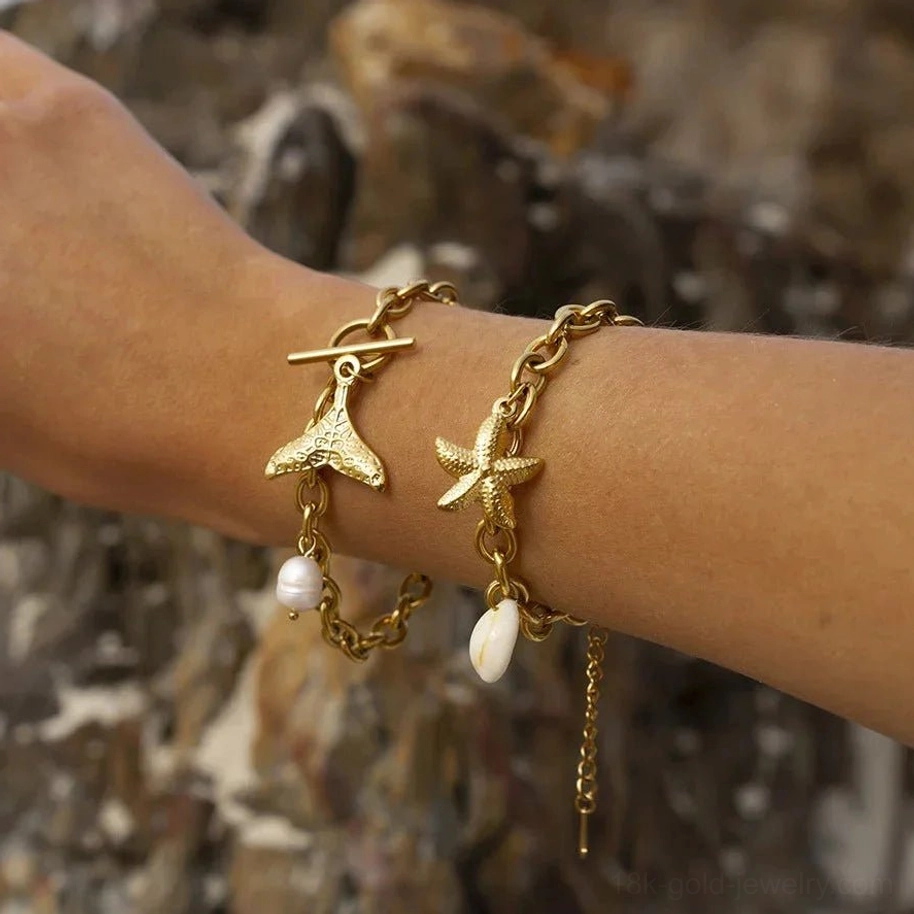 18k gold ocean charm bracelet worn on wrist close-up starfish mermaid tail shell charms