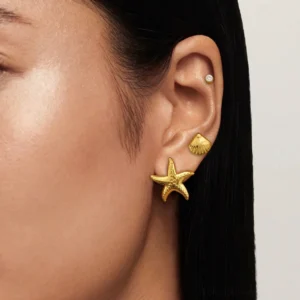 18K gold ocean earring set worn on female ear featuring starfish stud close-up view showcasing polished golden finish and crystal detail