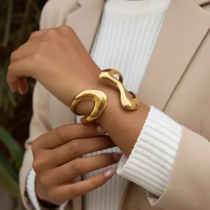 Two 18K gold sculptured bangles worn together on female wrist, close-up side view showing organic wave twisted design and smooth shiny gold finish