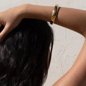 Woman wearing 18K gold open cuff bangle on wrist, back view demonstrating sleek polished gold finish and comfortable fit