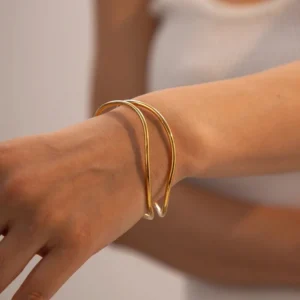 18K gold open cuff bracelet on woman's wrist, close-up side view, comfortable fit on arm, white tank top styling