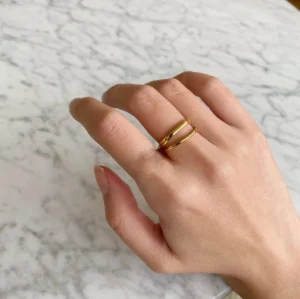 18K gold ring worn on hand side view close-up elegant dual-band cuff design on finger