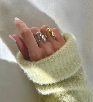 18K gold open wrap ring worn on female hand with chunky curved bands, mixed metal tones, close-up lifestyle shot