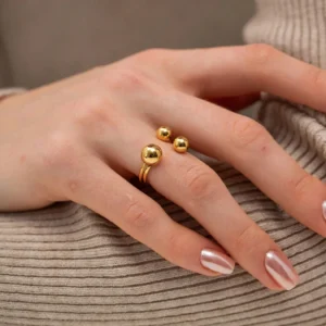 18K gold orbit ring worn on woman's hand close-up side view showing sleek polished gold finish against skin with chrome pink nail polish