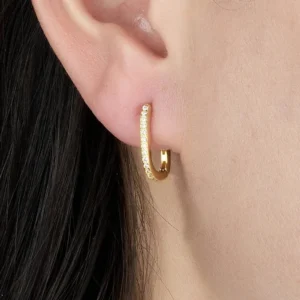 18K gold oval huggie hoop earrings on model ear close-up wearing shot showing fit and sparkle