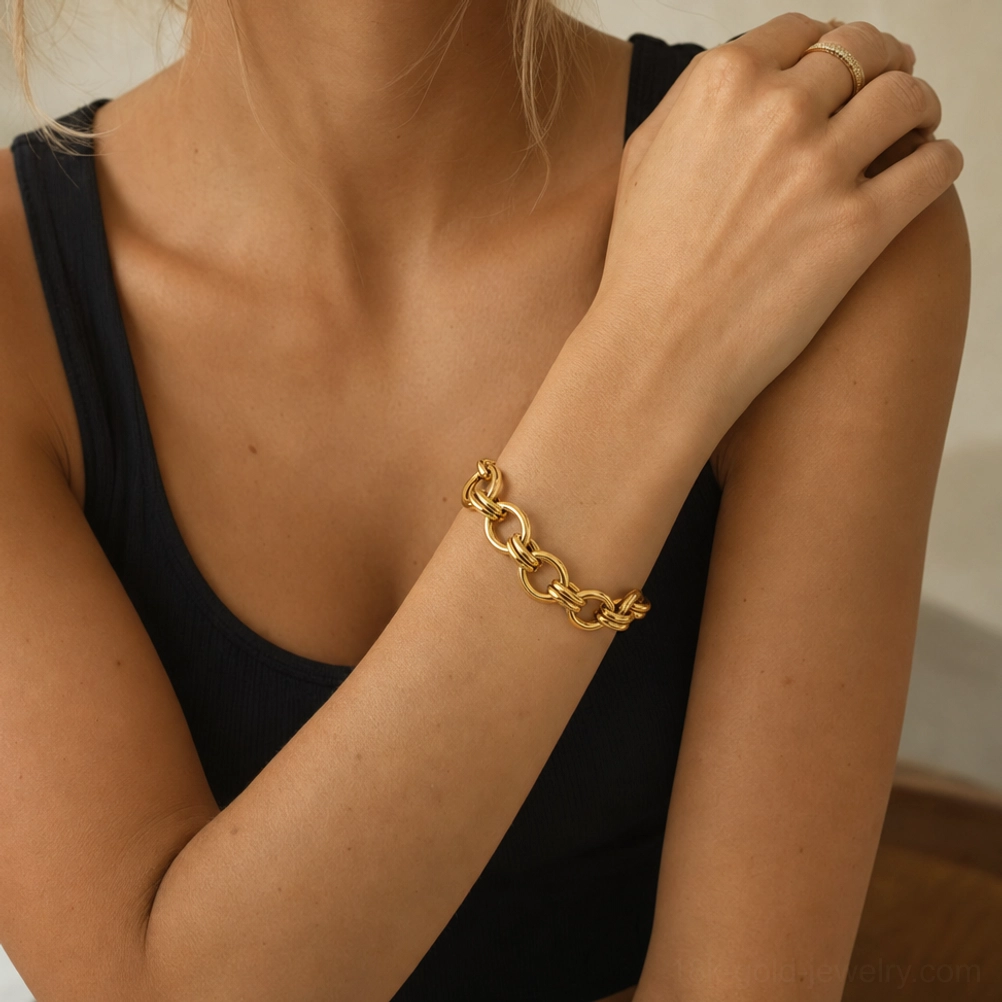 Elegant simple 18K gold oval link bracelet on female wrist front view black tank top sophisticated