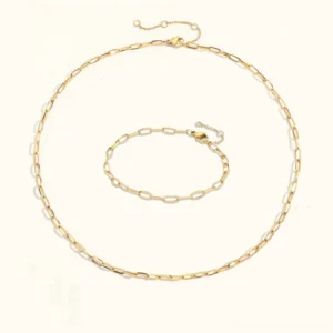 18K gold paperclip chain jewelry set flat lay featuring matching necklace and bracelet with oval links on white background