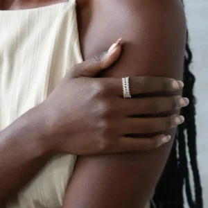 Slim pavé cubic zirconia gold band ring on hand, close-up side view showing minimalist elegant style and crystal details on dark skin tone model