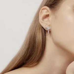 Silver-toned pavé knot stud earrings close-up on ear model showing delicate design and elegant rhinestone details on human ear