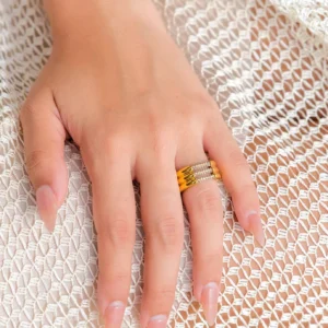 Close-up hand wearing 18K gold diamond simulant pavé stackable ring on knitted fabric