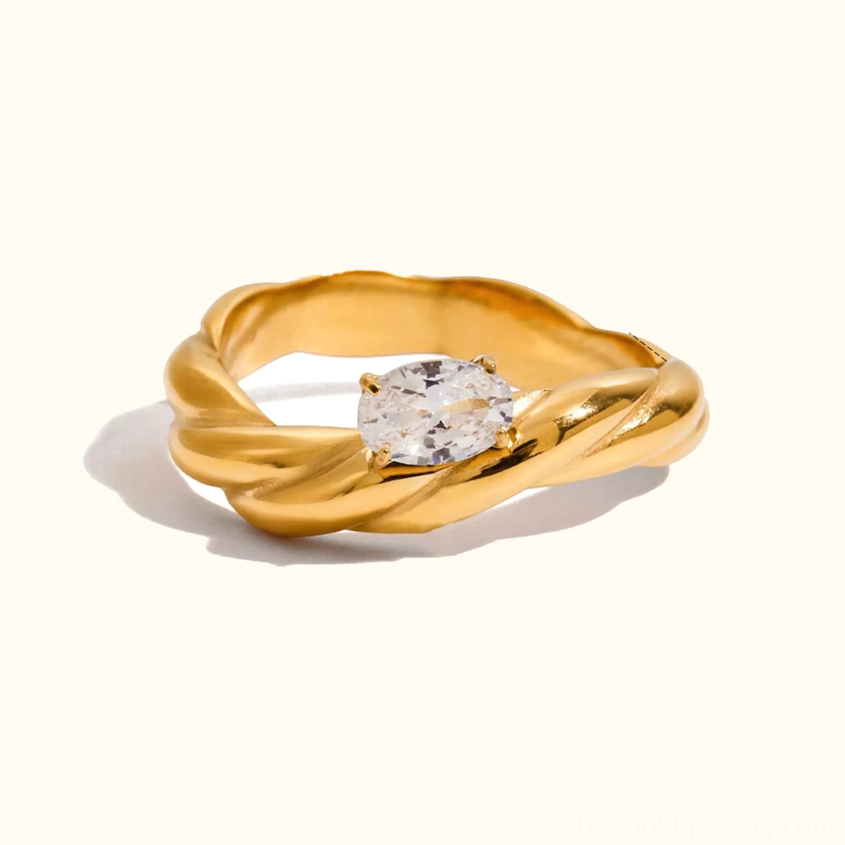 Close-up flat lay studio shot of twisted pear solitaire 18K gold ring with polished band