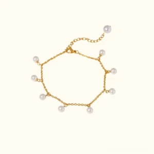 18K gold pearl anklet flat lay featuring slim gold chain with dangling freshwater pearls on off-white background