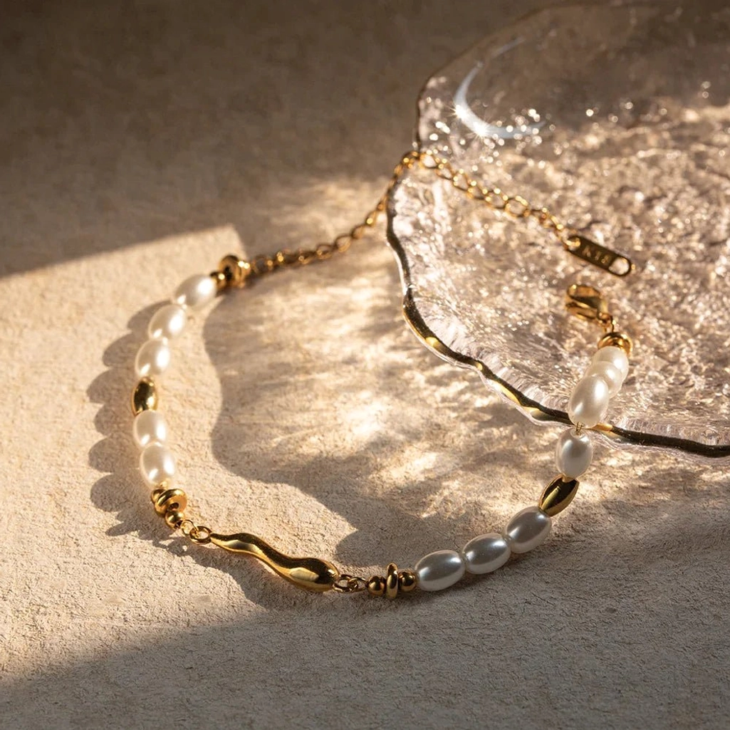 Close-up macro view of 18K gold pearl bracelet showing white oval pearls irregular twisted gold bars and metal spacer beads