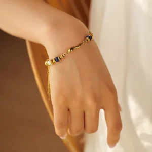18K gold chain bracelet with blue accent beads worn on female wrist, side view close-up showing pearl details and gold finish in warm indoor setting