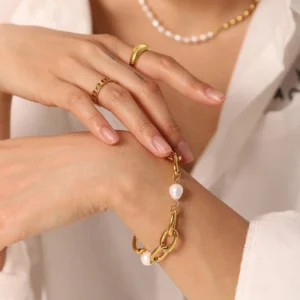 Freshwater pearl and gold chain bracelet worn on female model wrist with white blouse and layered mixed metal jewelry styling