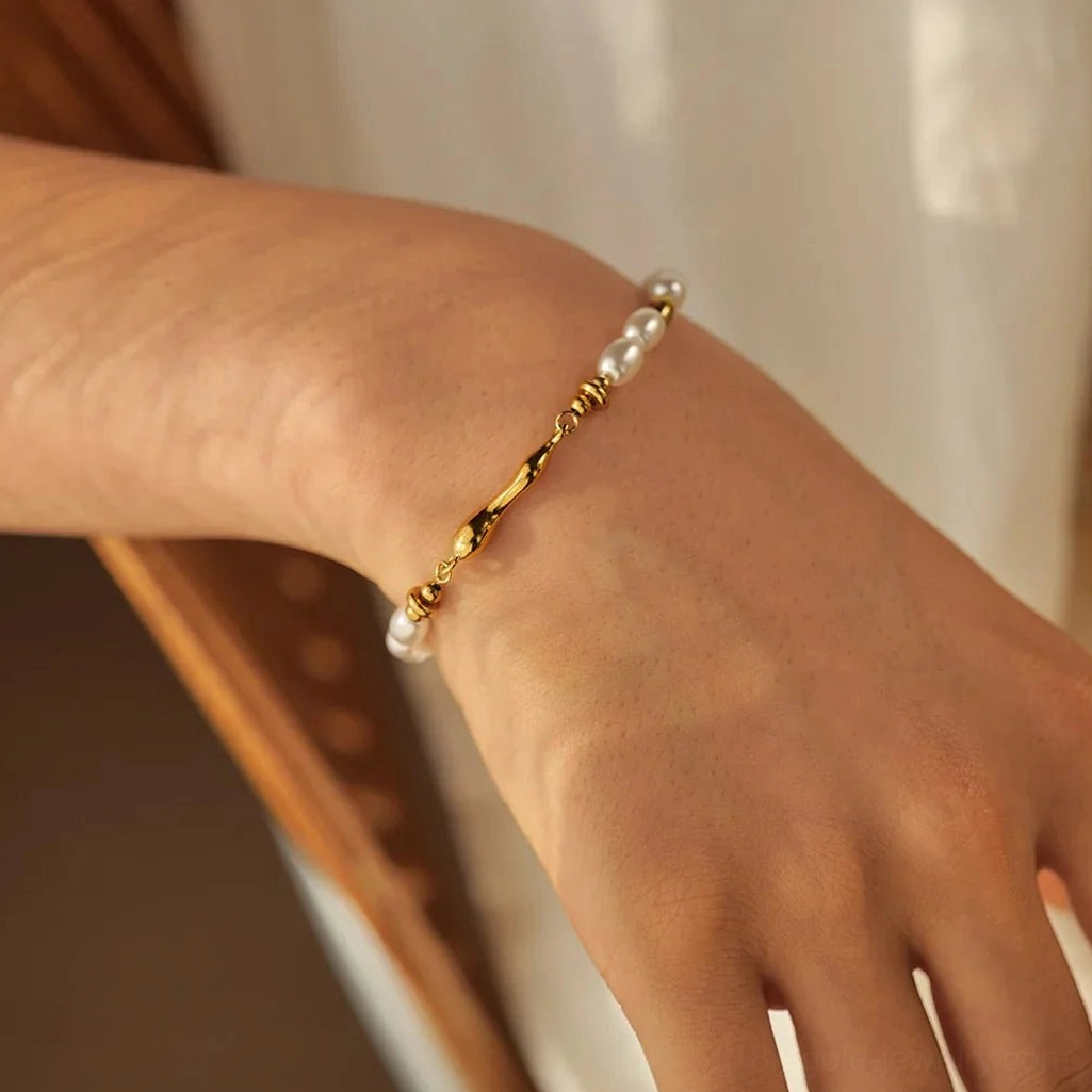 Elegant 18K gold pearl bracelet on female wrist close-up showing twisted gold chain segment and adjustable fit comfort