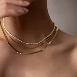 Pearl choker necklace worn on female model neck close-up showing elegant layered styling with additional gold chains