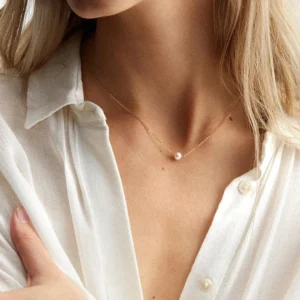 Minimalist freshwater pearl necklace worn on woman's neck with white button-down shirt lifestyle modeling tiny lustrous pearl pendant