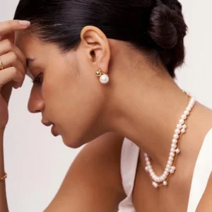 18K gold pearl stud earrings worn on model showing elegant side profile with minimalist pearl design and gold dome accent on ear