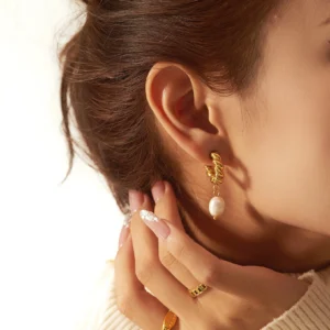 Close-up side view of 18K gold pearl earrings worn by woman, showing proper fit on earlobe and elegant pearl pendant with gold hoop