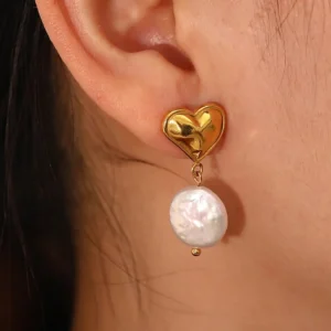 18K gold freshwater pearl earrings close-up on ear, showing baroque pearl pendant and polished gold hardware worn by model