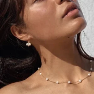 Woman wearing 18K gold pearl necklace and matching pearl drop earrings jewelry set on profile view