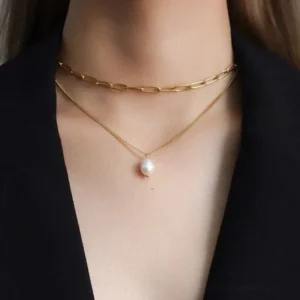 Woman wearing 18K gold layered pearl necklace choker with pearl pendant, black blazer professional styling