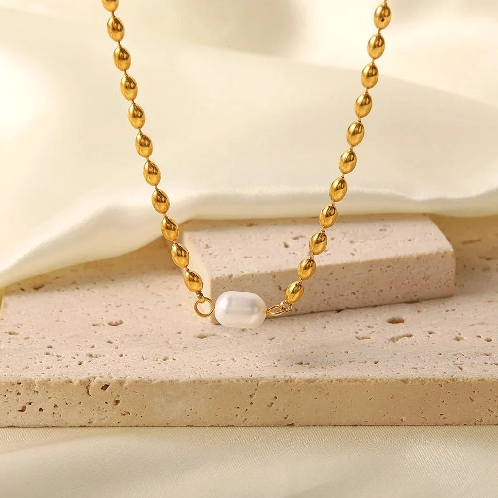 Delicate 18K gold beaded chain freshwater pearl necklace styled on beige fabric with natural stone props - lifestyle styling