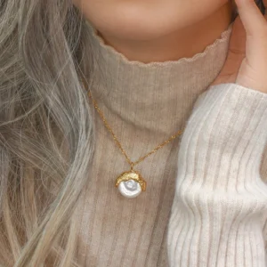 Woman wearing 18K gold pearl necklace at collarbone, styled with warm grey turtleneck sweater, casual everyday styling