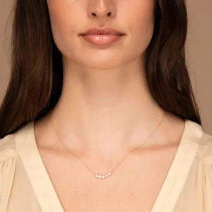 delicate 18K gold pearl necklace worn on woman collarbone dainty design linen top styling