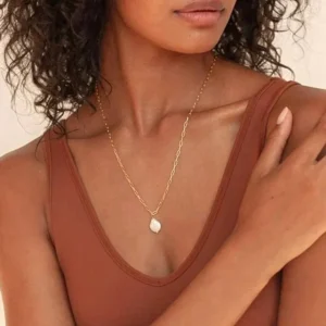 elegant baroque freshwater pearl necklace worn on collarbone of woman in brown tank top, close-up jewelry portrait