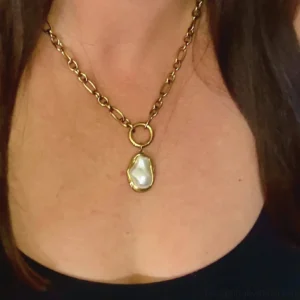 Baroque pearl gold necklace worn by woman at collarbone demonstrating how pendant sits on neck with polished gold hardware detail