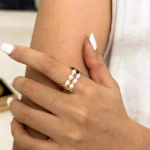 Woman's hand wearing Elliana 18K gold pearl ring on index finger, close-up detail shot showing pearl arrangement and gold finish
