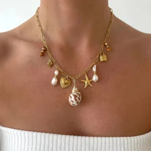 Pearl seashell charm necklace worn on neck close-up showcasing warm 18K gold hardware and dangle ocean motifs on model