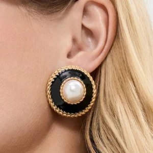 Pearl stud earrings worn on ear, 18K gold with black enamel detail, modeled on blonde woman, close-up side angle shot showing real-life wear