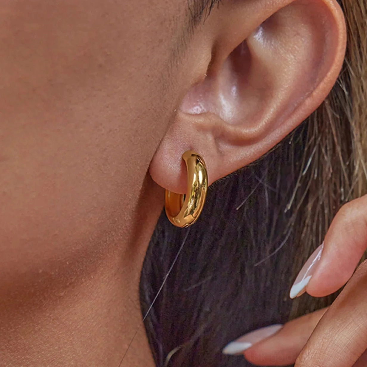 Thick petite gold huggie hoop earrings 14mm on ear showing polished finish and snug fit