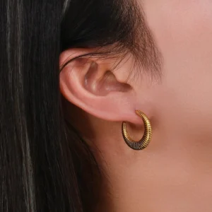 Gold ribbed hoop earrings worn on ear close-up view demonstrating fit and textured C-shape design on model