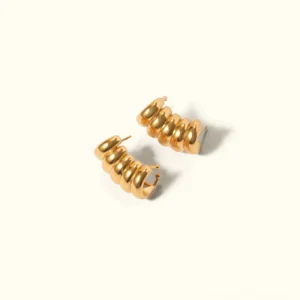 18K gold ridged hoop earrings flat lay featuring polished textured curved design on light beige background