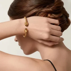 Close-up side view of 18K gold twisted cable cuff bracelet worn on model, showing rope texture and gemstone accents