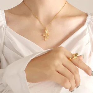 Woman wearing 18K gold rose pendant necklace at collarbone styled with white ruffled blouse and gold accessories