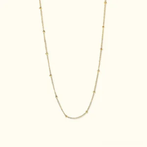 18K gold satellite chain necklace flat lay overhead view featuring delicate gold cable with evenly spaced spherical beads on light background
