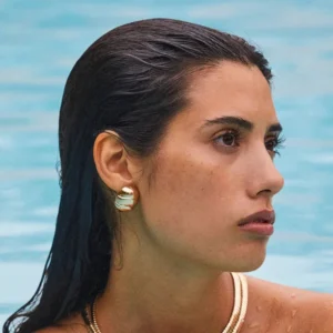 woman wearing gold scarab earrings in swimming pool water lifestyle photo profile view